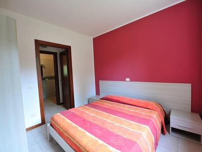 Bedroom with double bed, red accent wall, and wooden furniture in a hotel room.