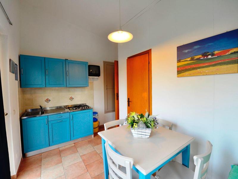 Small kitchen and dining area with blue cabinets and white table in a hotel room.