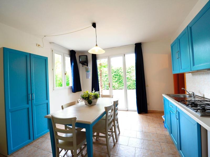 Bright kitchen with blue cabinets, dining table, and large windows facing the garden