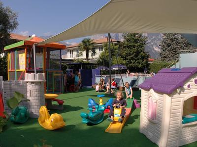 Bunter Kinderspielplatz mit Spielhaus und Rutschen in einem Hotelgarten