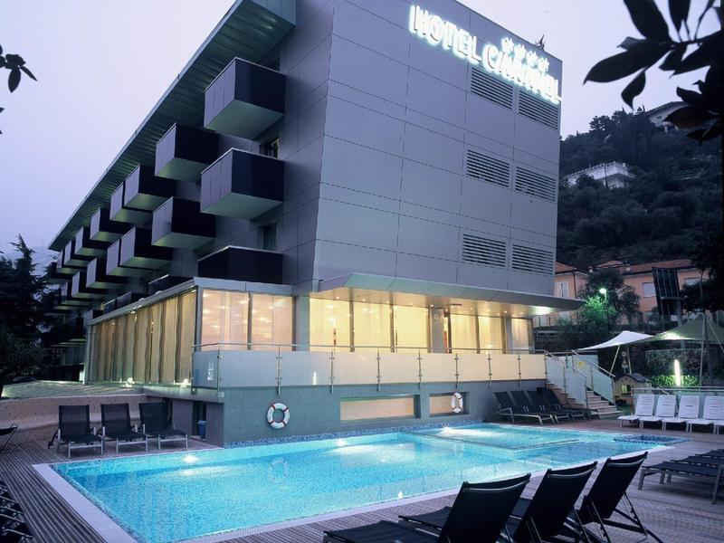 Edificio hotel moderno con insegna illuminata e piscina all'aperto illuminata.