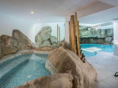 Moderner Hotelinnenpool mit Felsen, Whirlpool und entspannenden Liegestühlen.