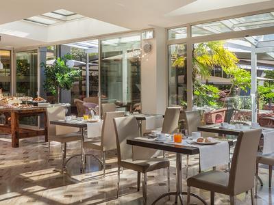 Helles Restaurant mit Glastüren, Blick auf Garten und gedeckten Tischen.