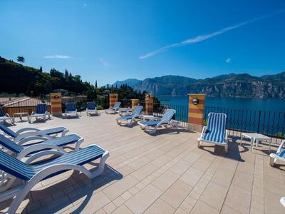 Terrace with lounge chairs overlooking lake and mountains on a sunny day.