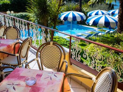 Balcony with set tables overlooking a pool with blue umbrellas.
