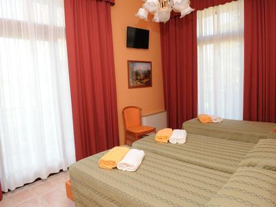 Hotel room with two single beds, brown curtains, and a small wall-mounted TV.