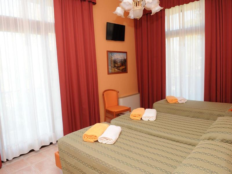 Hotel room with two single beds, brown curtains, and a small wall-mounted TV.