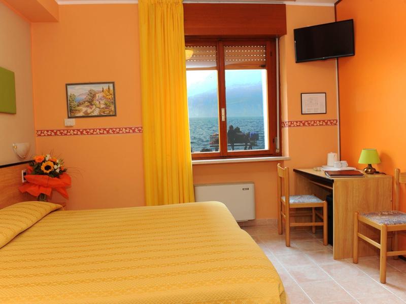 Cozy hotel room with yellow bed, curtain, and desk by the window.