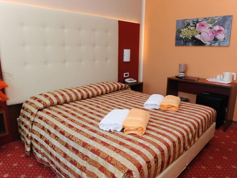 Cozy hotel room with double bed, striped bedding, and towels placed on the bed.