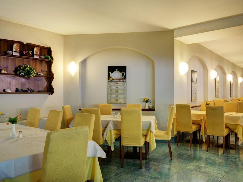 Comedor iluminado con sillas amarillas y manteles blancos en un hotel.