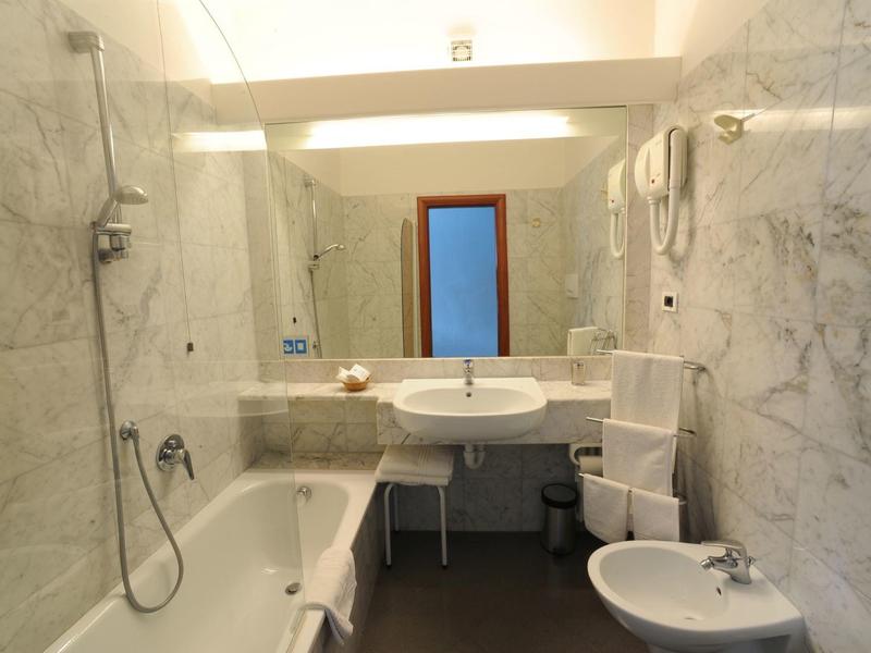 Bagno luminoso con pareti in marmo, vasca da bagno, lavabo e bidet.