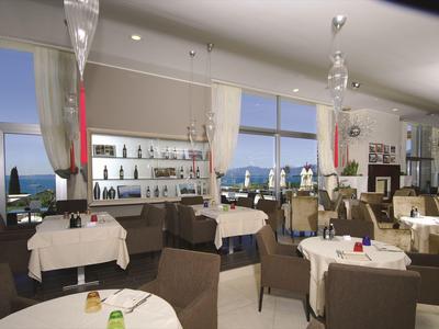 Elegantes Restaurant mit bequemen Stühlen und Fensterblick auf das Meer bei Tageslicht.