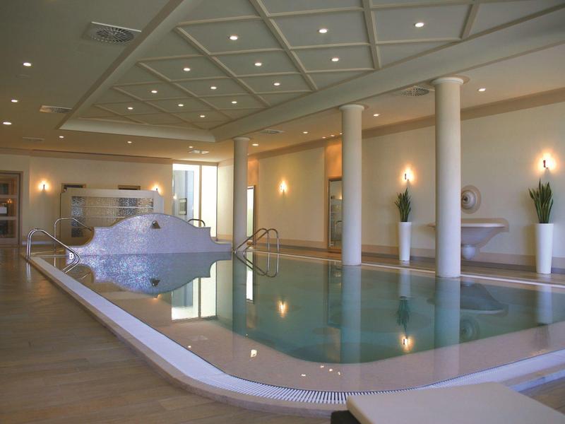 Modern indoor pool with waterfall feature and elegant lighting in a hotel