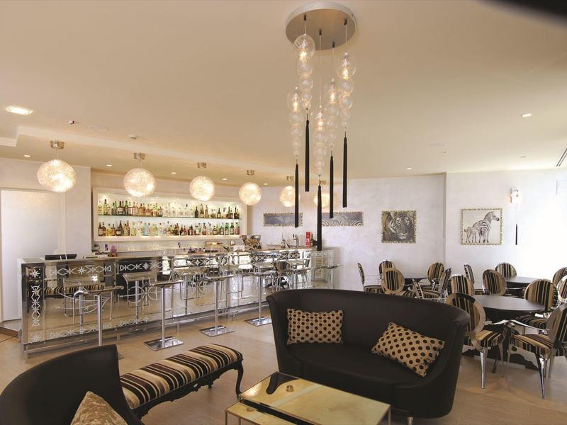 Bright hotel bar with modern furniture, seating areas, and a well-stocked counter.
