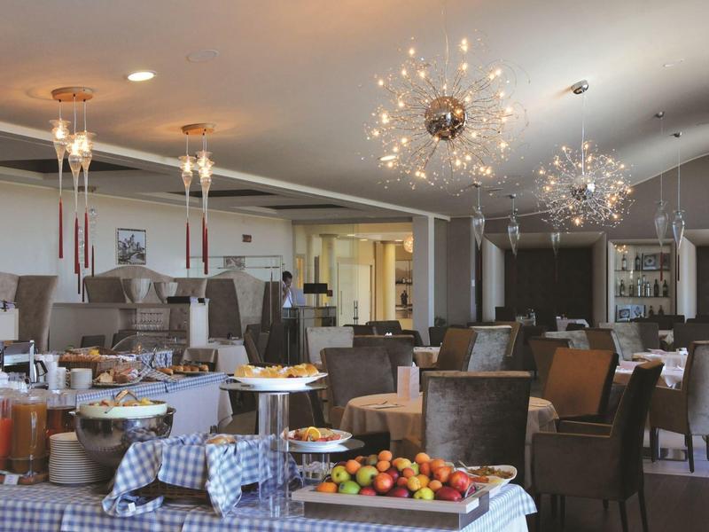 Elegant restaurant with set tables and buffet featuring fruit and sauces.