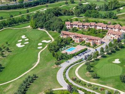 Aerial view of a hotel with pool and golf course in a green landscape.