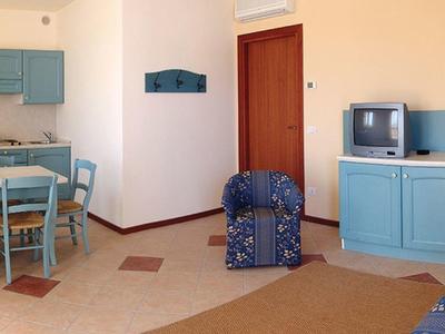 Bright living room with dining table, chairs, sofa, and TV in blue tones.