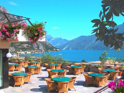 Terrasse avec tables et chaises avec vue sur les montagnes et le lac sous un ciel dégagé.