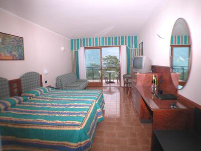 Jasny pokój hotelowy z dwoma łóżkami, balkonem i widokiem na morze.