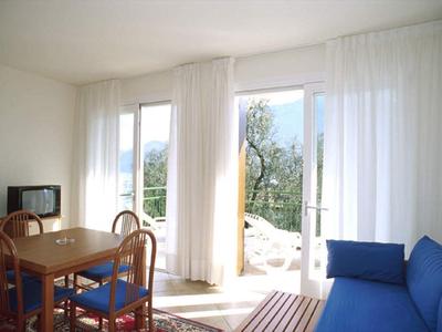 Jasny salon z stołem jadalnym, krzesłami, niebieską sofą i dostępem do tarasu i ogrodu