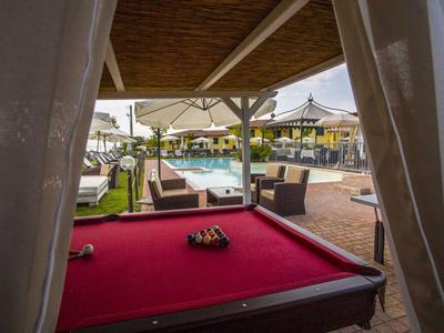 Rot beleuchteter Billardtisch im Freien mit Blick auf Liegestühle und Sonnenschirme.