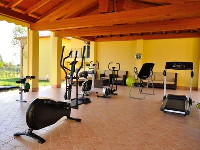 Fitnessraum mit verschiedenen Trainingsgeräten in einem Hotel mit holzverkleidetem Dach.