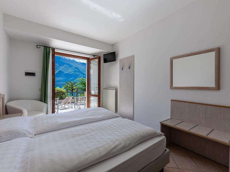 Heller Schlafzimmer mit zwei Einzelbetten, weißer Einrichtung und offener Tür zur Berglandschaft.