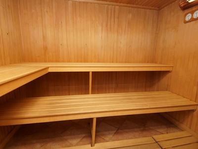 Sauna mit hellen Holzplanken, zweistufigen Bänken und warmem, natürlichem Licht.