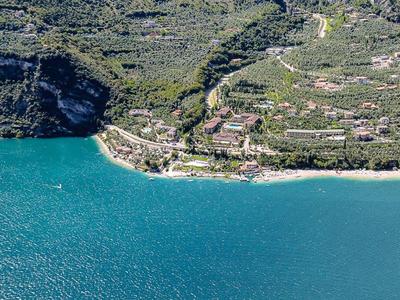 Küstenlinie mit klarem blauem Wasser, steilen Felsen und grüner Vegetation. Kleine Häuser am Hang.