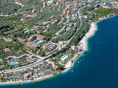 Luftaufnahme einer Küstenstadt mit vielen Häusern, grünen Bäumen und blauem Meer.