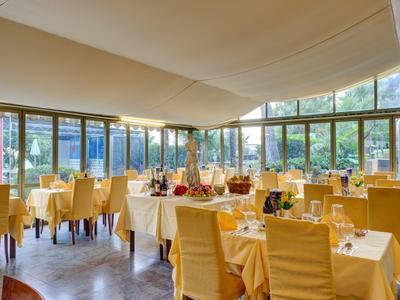 Ein helles Restaurant mit großen Fenstern, gelben Stühlen und sorgsam gedeckten Tischen.