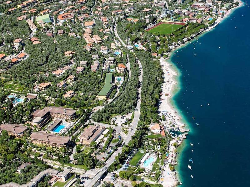 Luftaufnahme einer Küstenstadt mit Stränden, grünen Hügeln und mehreren Straßen entlang des Meeres.
