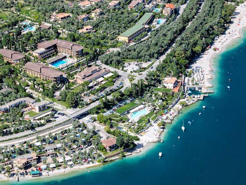 Luftaufnahme einer Küstenstadt mit Stränden, Gebäuden und grünen Flächen am klaren blauen Meer.