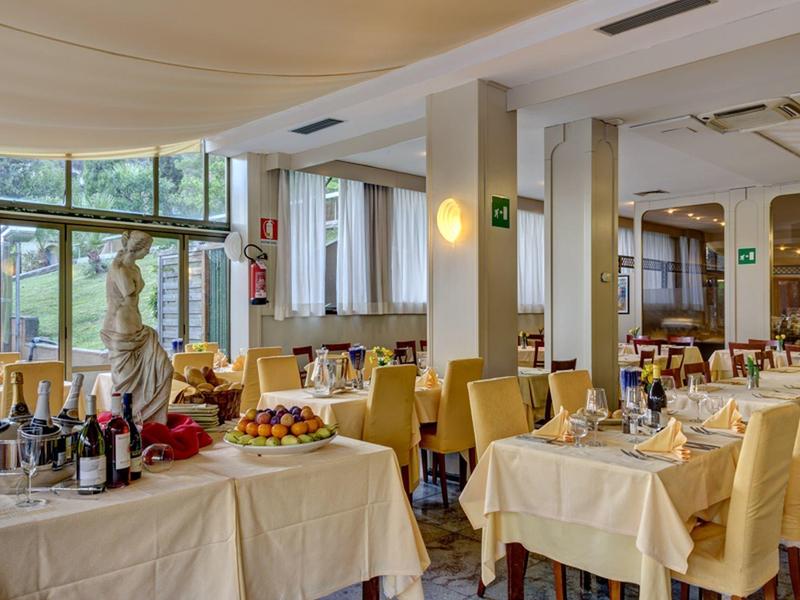 Helles Restaurant mit großen Fenstern, gedeckten Tischen und Buffets mit Speisen und Getränken.