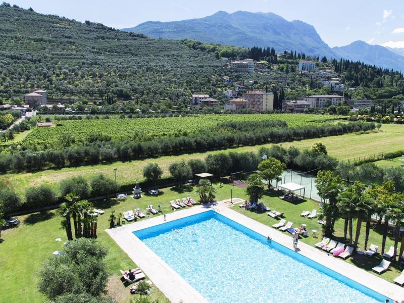 Großer rechteckiger Pool mit klar blauem Wasser, umgeben von Liegestühlen und Grünflächen, im Hügelgebiet.