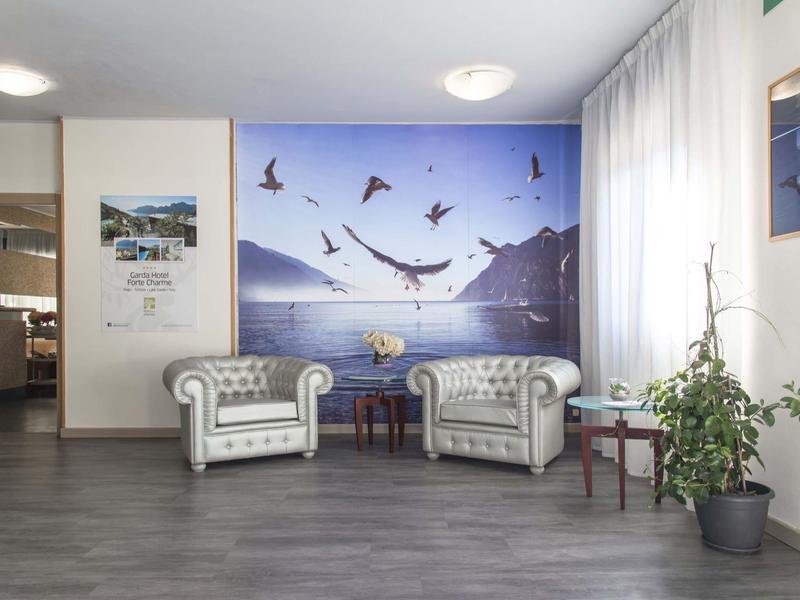 Gemütliche Sitzecke mit zwei grauen Sesseln, Meeresbild und Pflanze im hellen Raum mit grauem Boden.