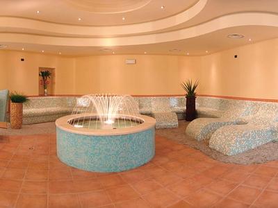 Relaxation area with curved seating, fountain, and warm lighting in hotel lounge.