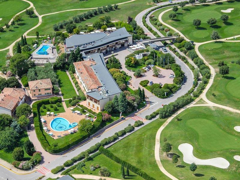 Aerial view of a golf hotel with multiple pools, buildings, and golf courses.