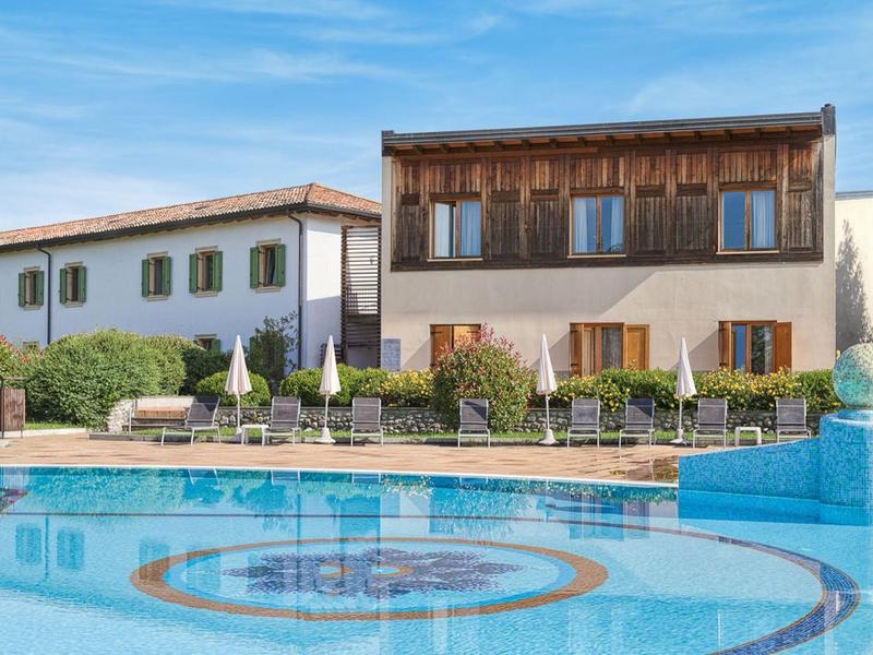 Two houses in front of a pool with clear water under a blue sky