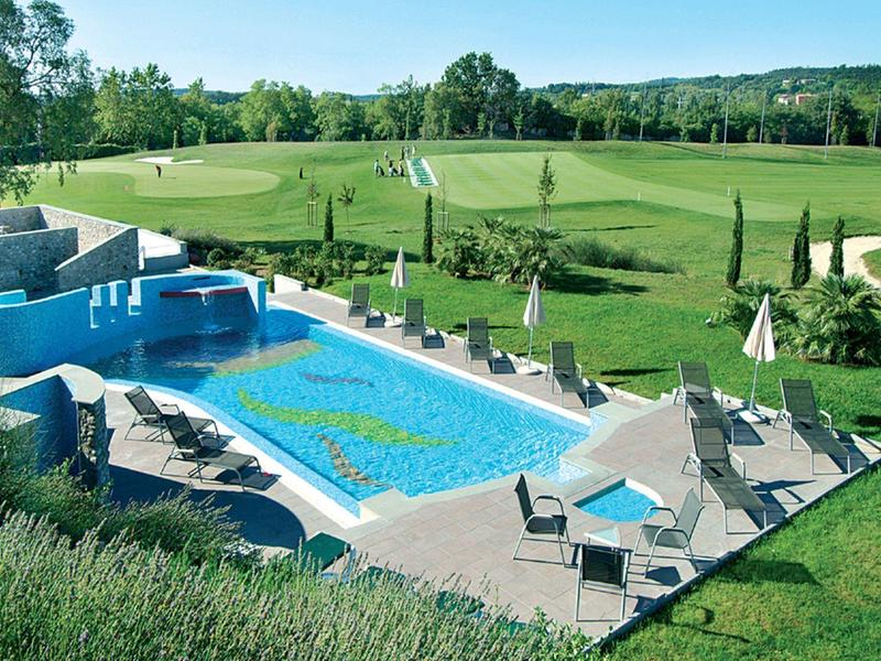Modern outdoor pool with sun loungers on a terrace next to a golf course