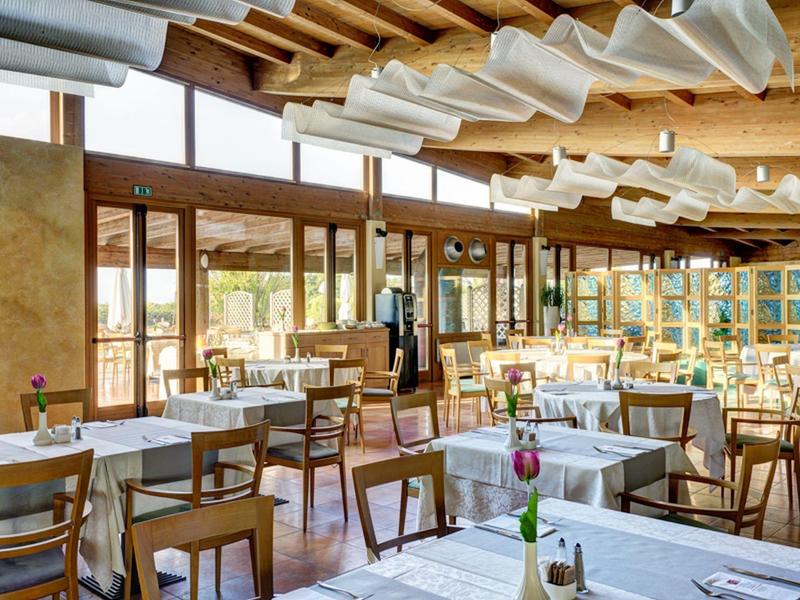 Bright restaurant with wooden beam ceiling, white tablecloths, and large windows