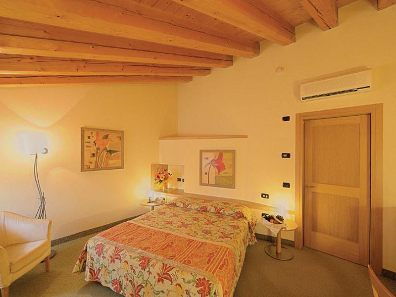 Cozy bedroom with wooden beam ceiling, double bed, and warm lighting.