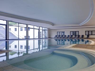 Piscina interna moderna con ampie finestre e lettini in un hotel.