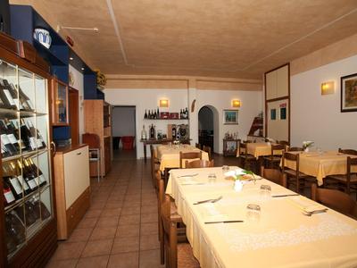 Een gezellige restaurant met houten meubels, gedekte tafels en wijnrekken aan de muur.