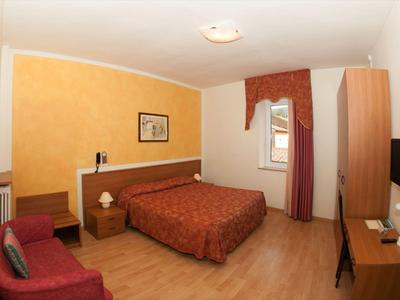 Une chambre d'hôtel simplement meublée avec un lit double, une armoire et un bureau.