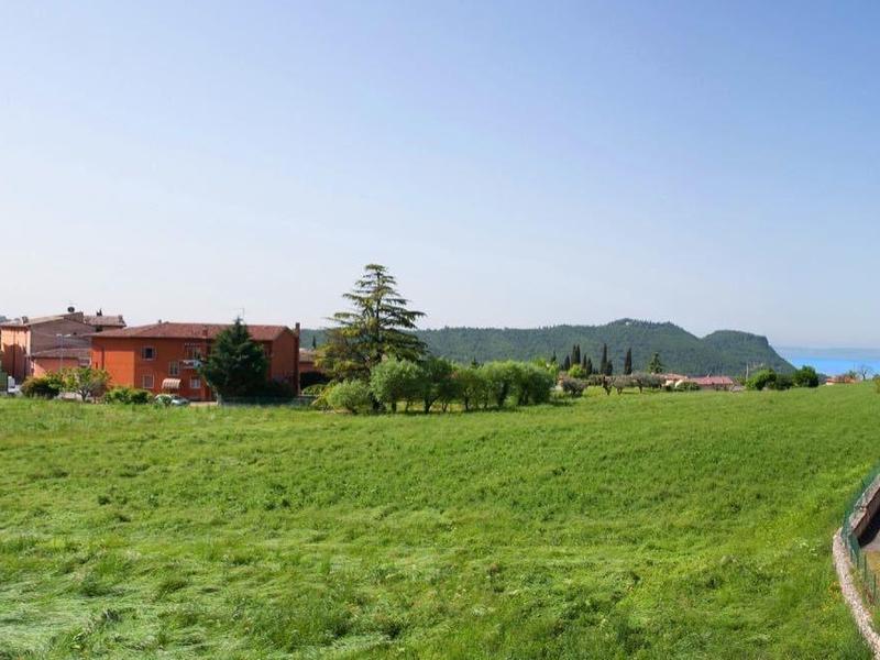 Champ vert avec des maisons et ciel dégagé en arrière-plan.