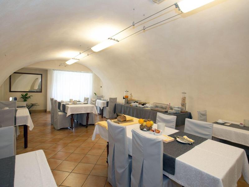 Restaurant lumineux avec nappes blanches, tables dressées et chaises modernes dans une salle voûtée.