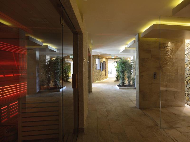 Moderner Flur mit warmem Licht, Steinwänden und Pflanze in der Mitte, reflektierende glasscheibe links.