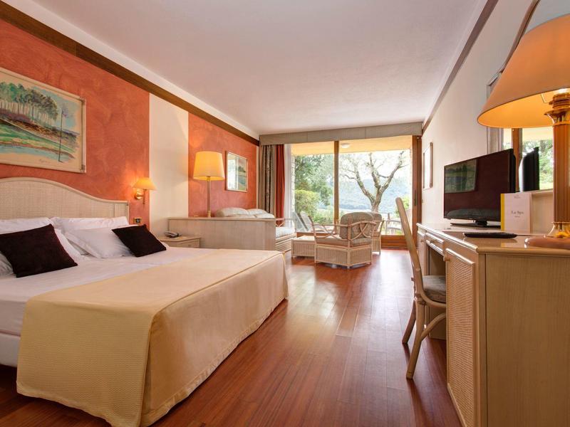 Helles Hotelzimmer mit zwei Betten, Holzboden, Fensterfront und schlichtem, modernem Mobiliar.