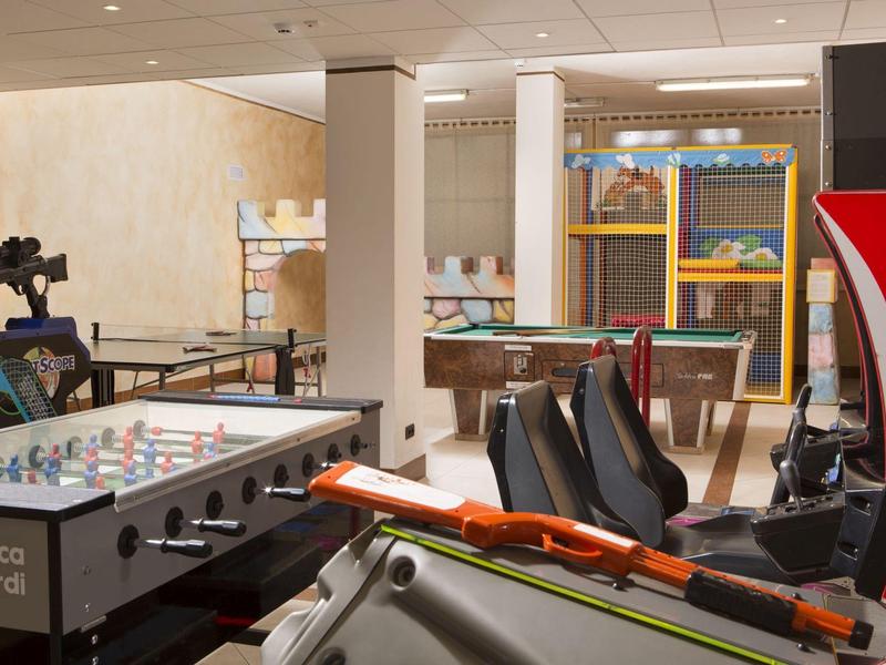 Ein Spielzimmer mit Kicker, Billardtisch, Sitzplätzen und Arcade-Spielautomaten.